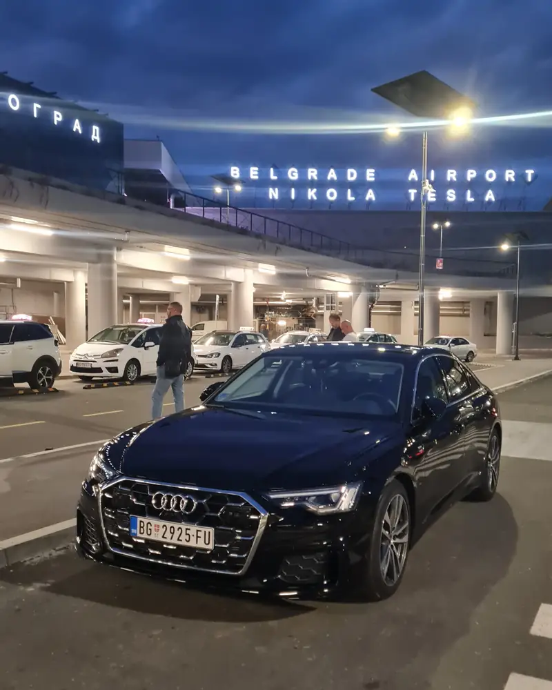 Crni Audi A6 Transfera Putnika ispred aerodroma Nikola Tesla noću