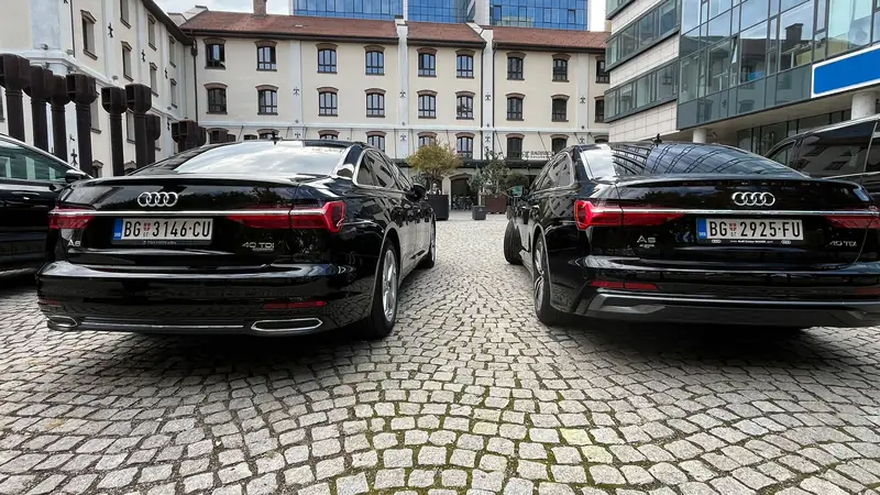 Dva crna Audi A6 Transfera Putnika parkirana na kaldrmi u Beogradu